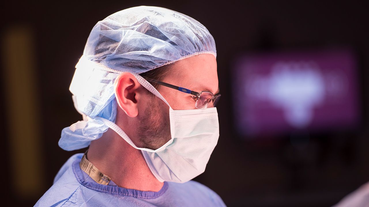 Side view of surgeon wearing mask and hair mask with glasses and scrubs