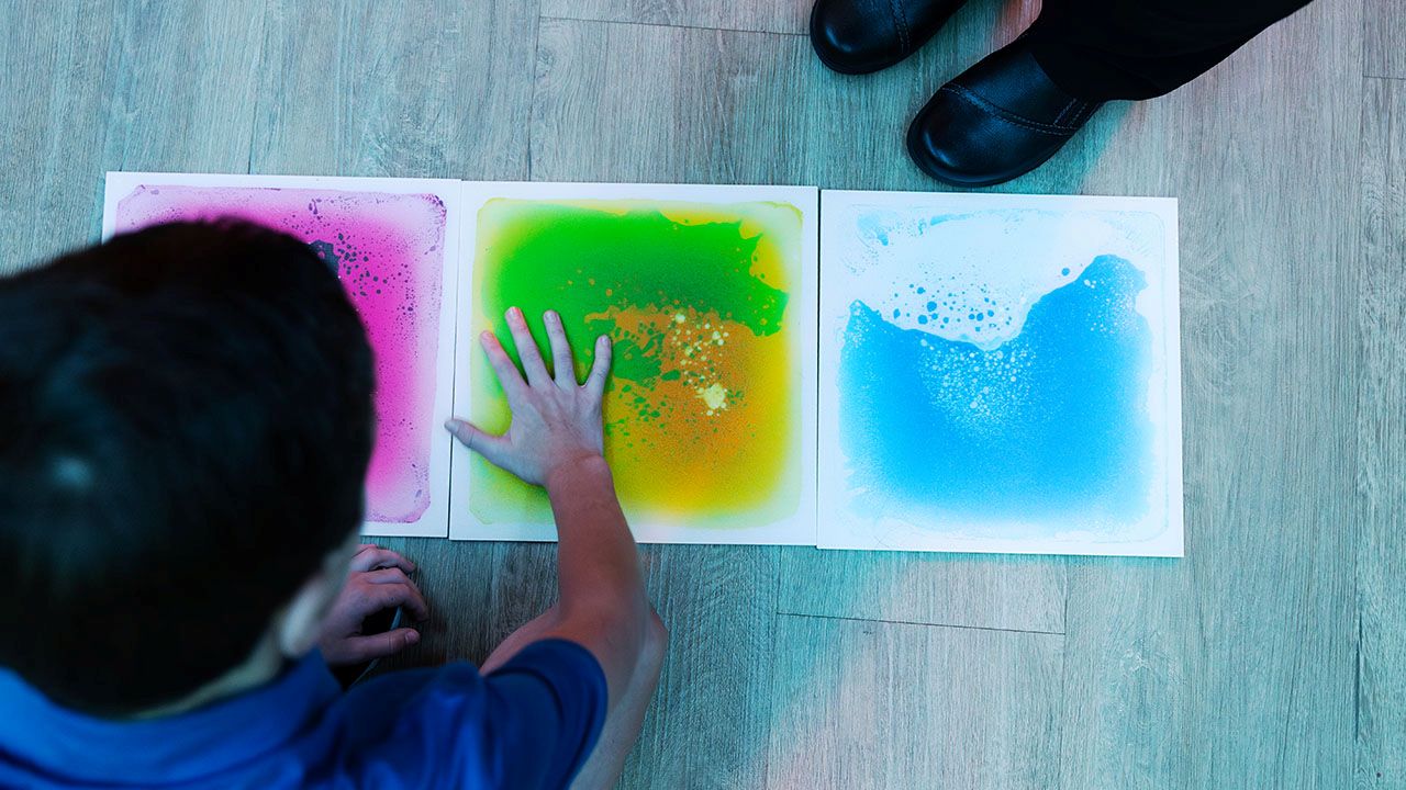 A child places a handprint on colorful images.