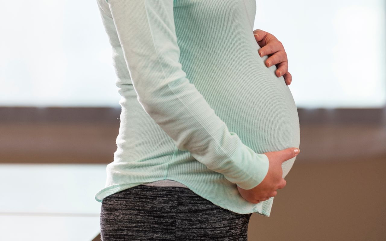 A pregnant person shows their baby bump.