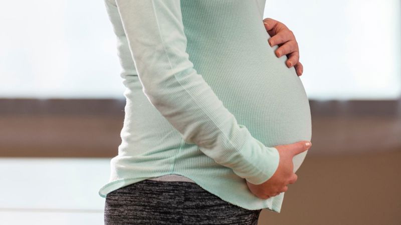 A pregnant person shows their baby bump.