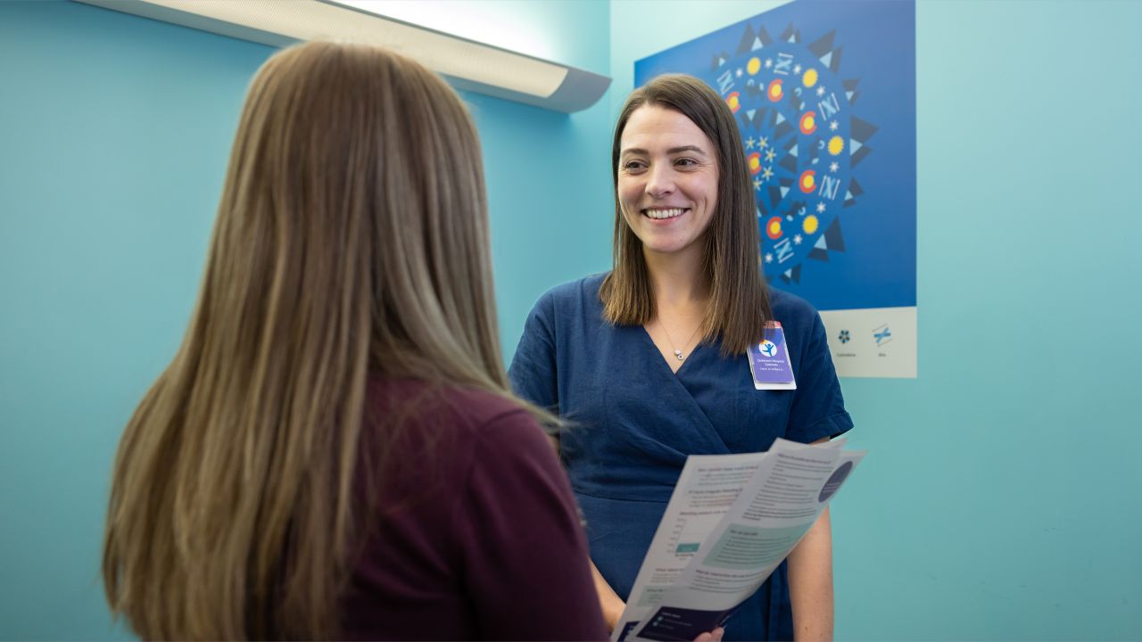 A female doctor holding papers talking to a patient