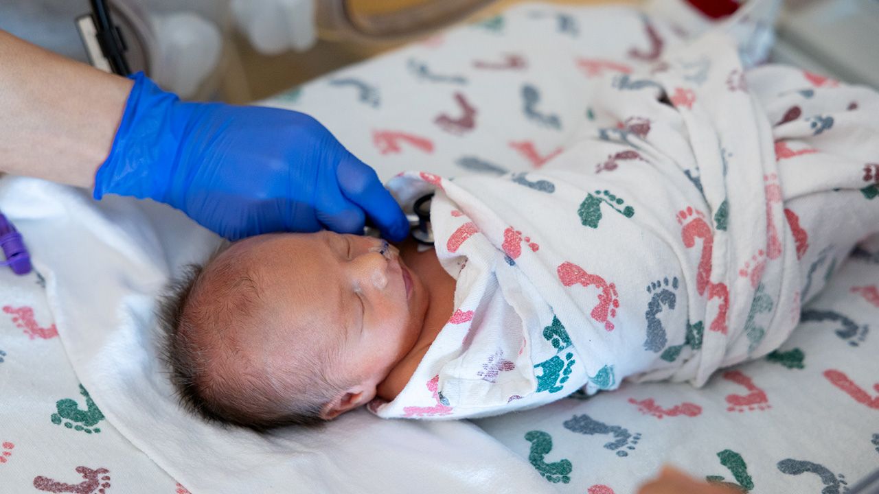 NICU patient wrapped in white blanket with footprints