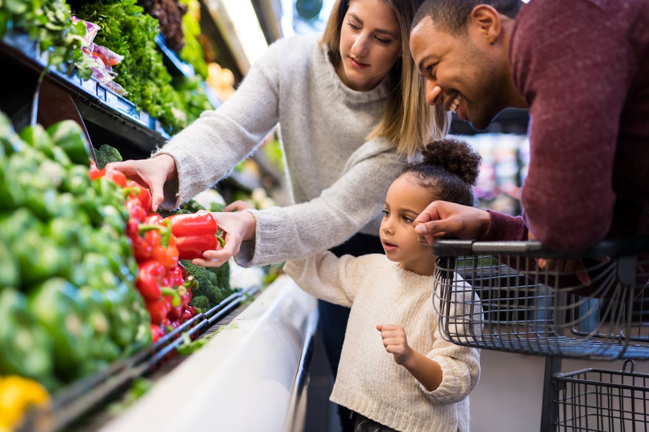 “Family at grocery store reaching for peppers”