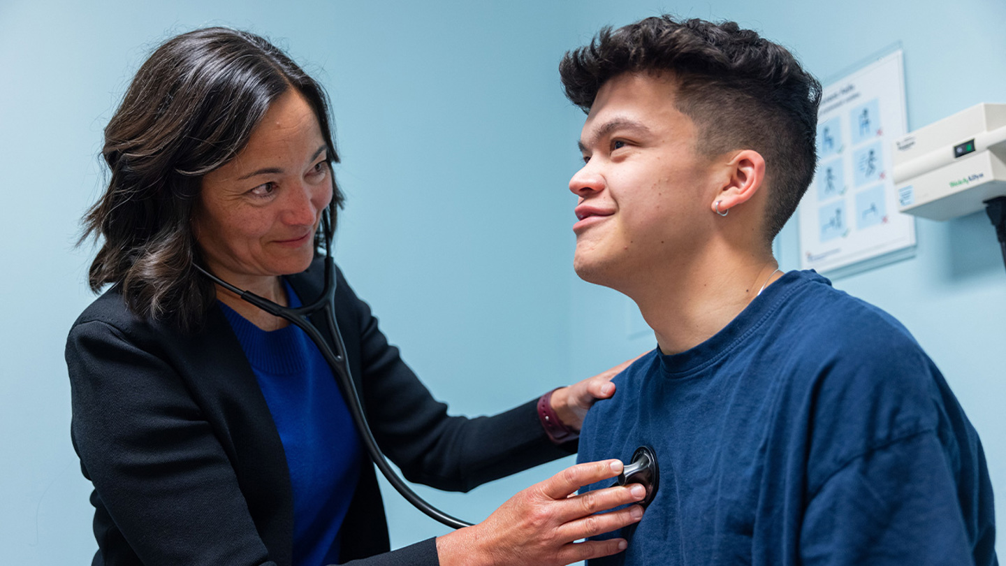 Healthcare provider using a stethoscope to listen to a patient’s heart during a clinic exam.