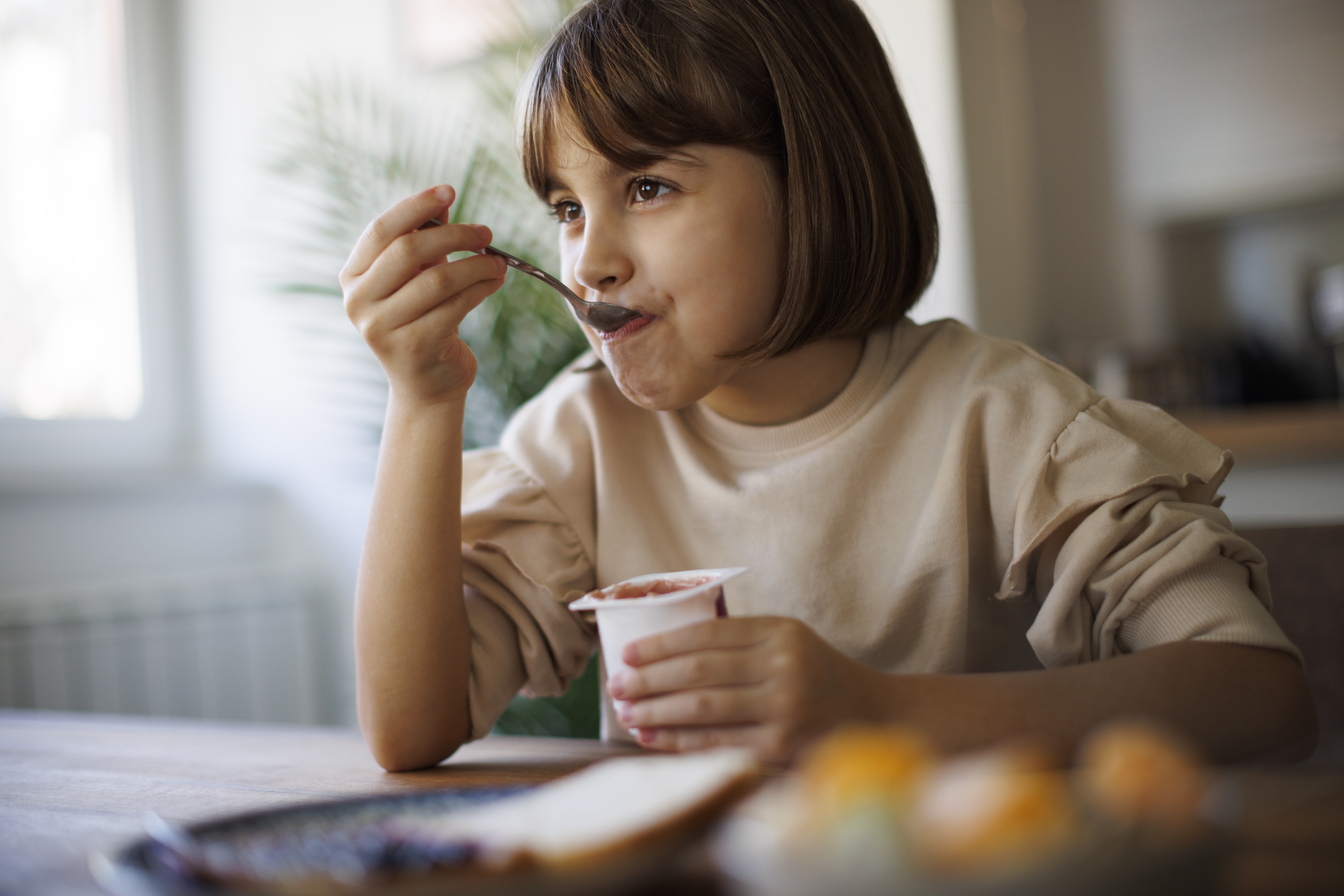 A child happily eats some yogurt.