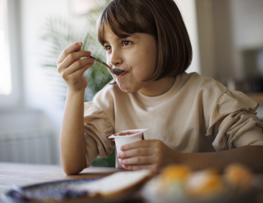 A child happily eats some yogurt.