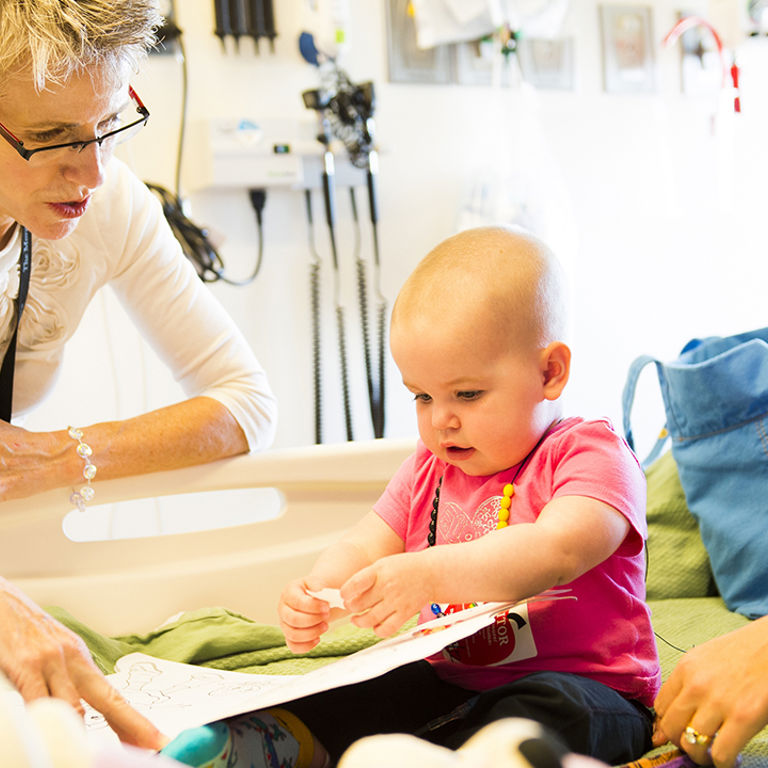 A medical provider at Children's Hospital Colorado talks with a toddler and her family in the Center for Cancer and Blood Disorders.