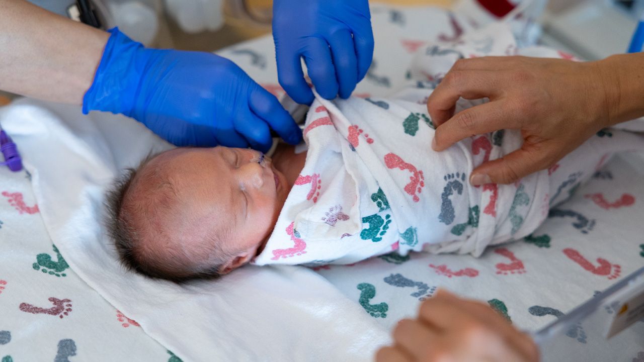 Newborn baby being wrapped in a footprint swaddle by healthcare workers