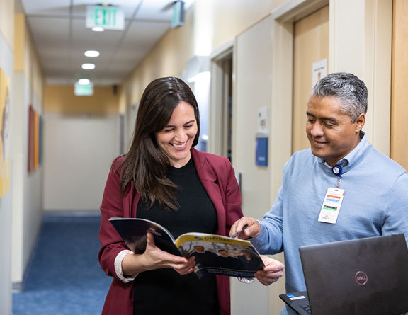 Two providers look at a brochure in the hallway of Children's Hospital.