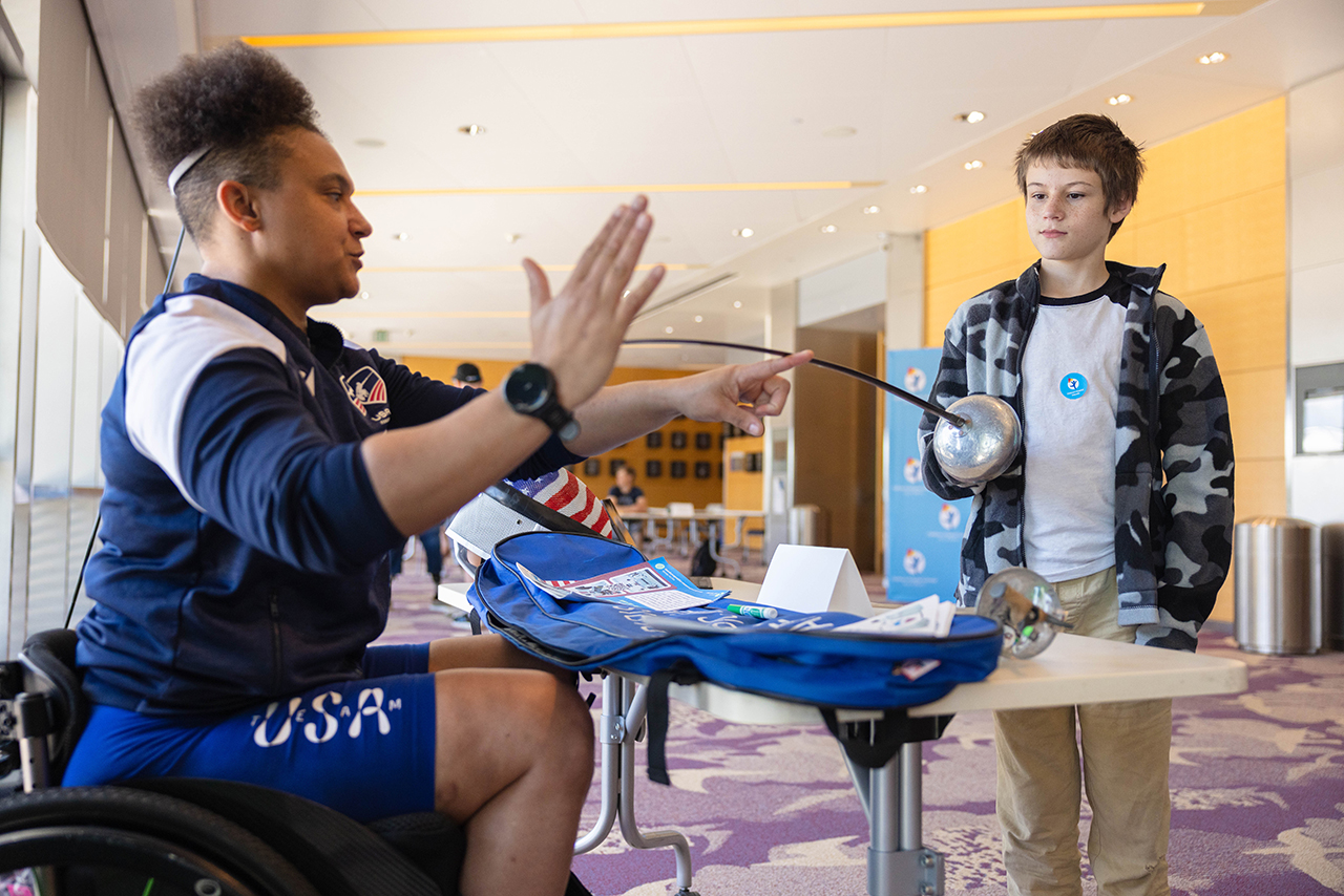 Patient holding a fencing sword with a Paralympian  athlete
