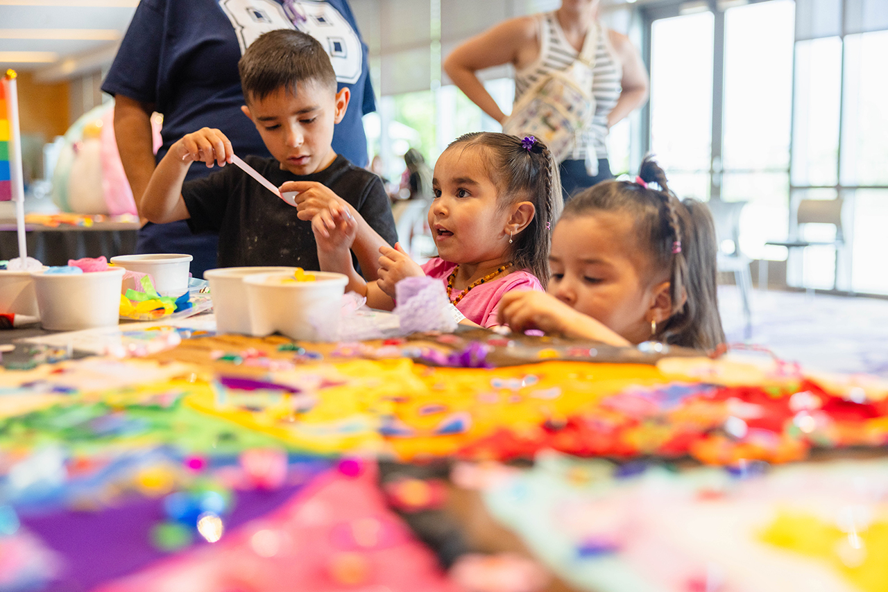  Three kids working on a colorful art project.