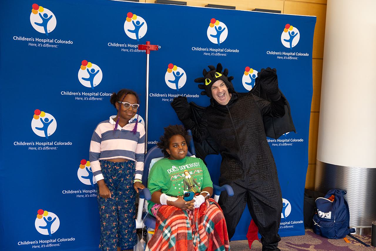 Guy dressed in a Toothless "How to Train Your Dragon" costume with patients  