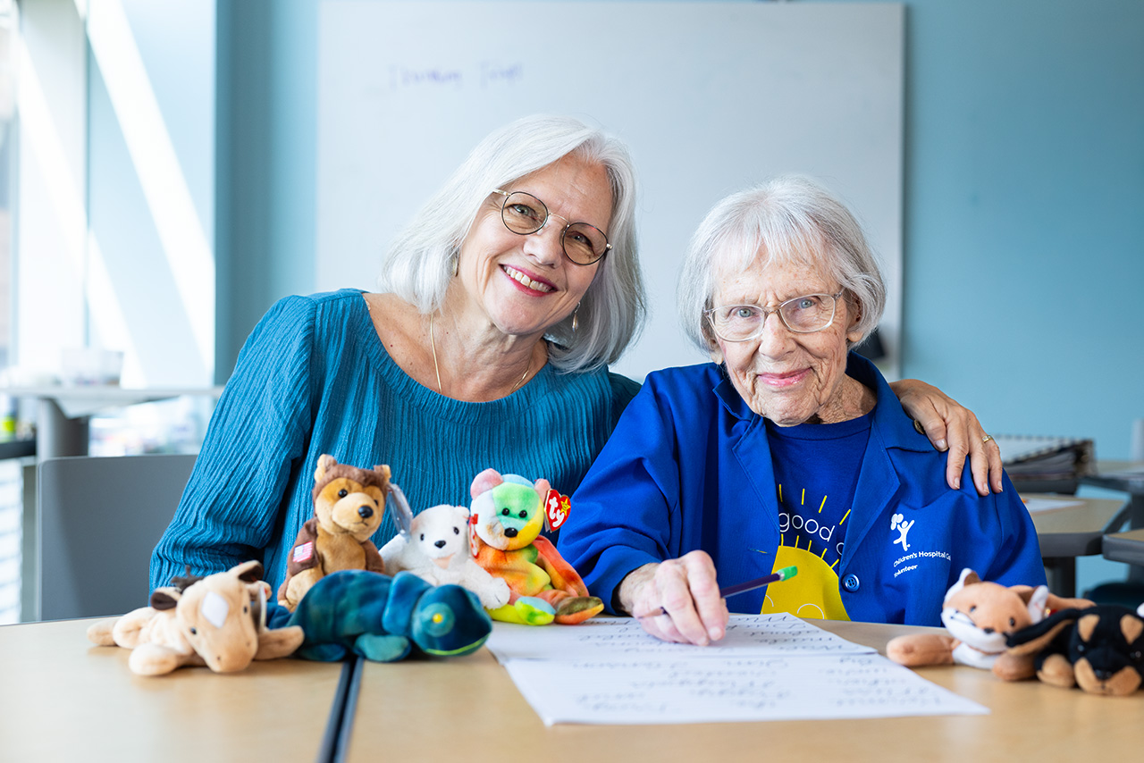 Jennifer and Fran Hagman, volunteers apart of the eating disorder program smiling sitting at a table 
