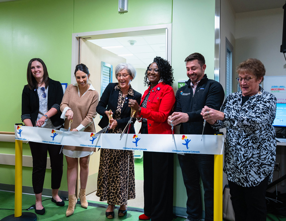 Group of people cutting a ribbon at the north campus behavioral health unit opening.