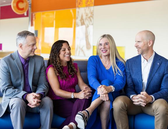 The podcast hosts from Charting Pediatrics and Pediatras en Linea pose in a Children's waiting room.