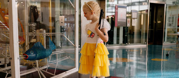Girl in a yellow dress watches the ball machine in the Children's atrium