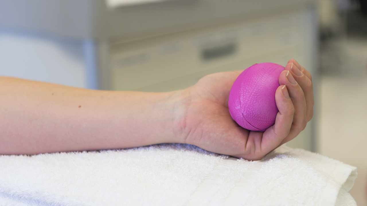 A person squeezes a pink foam ball while donating platelets at Children's Hospital Colorado.