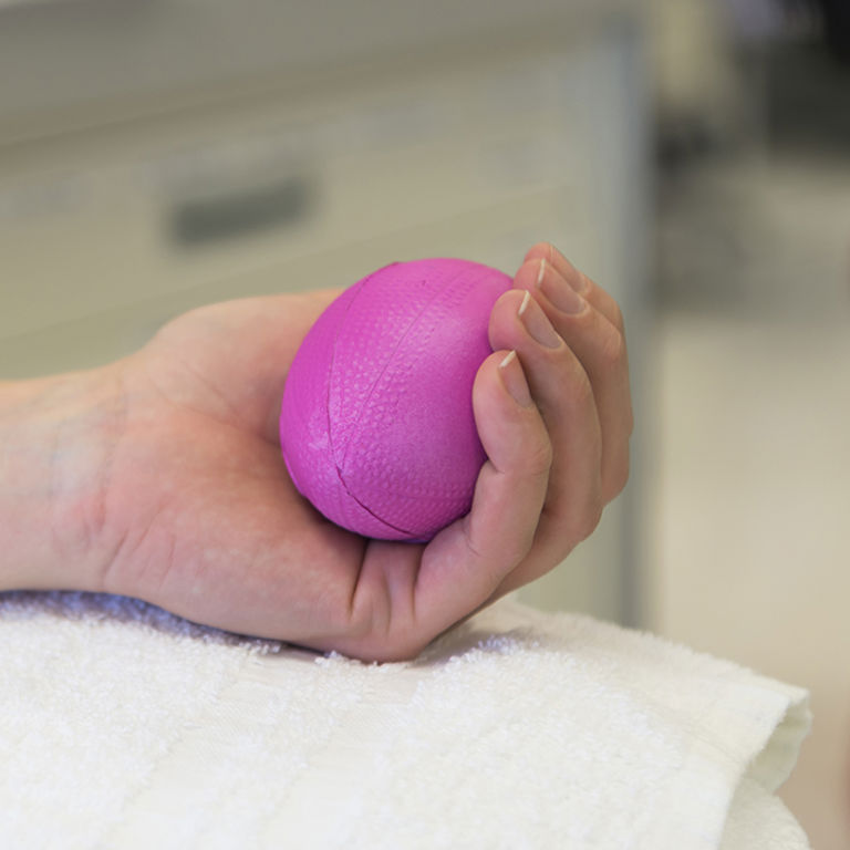 A person squeezes a pink foam ball while donating platelets at Children's Hospital Colorado.