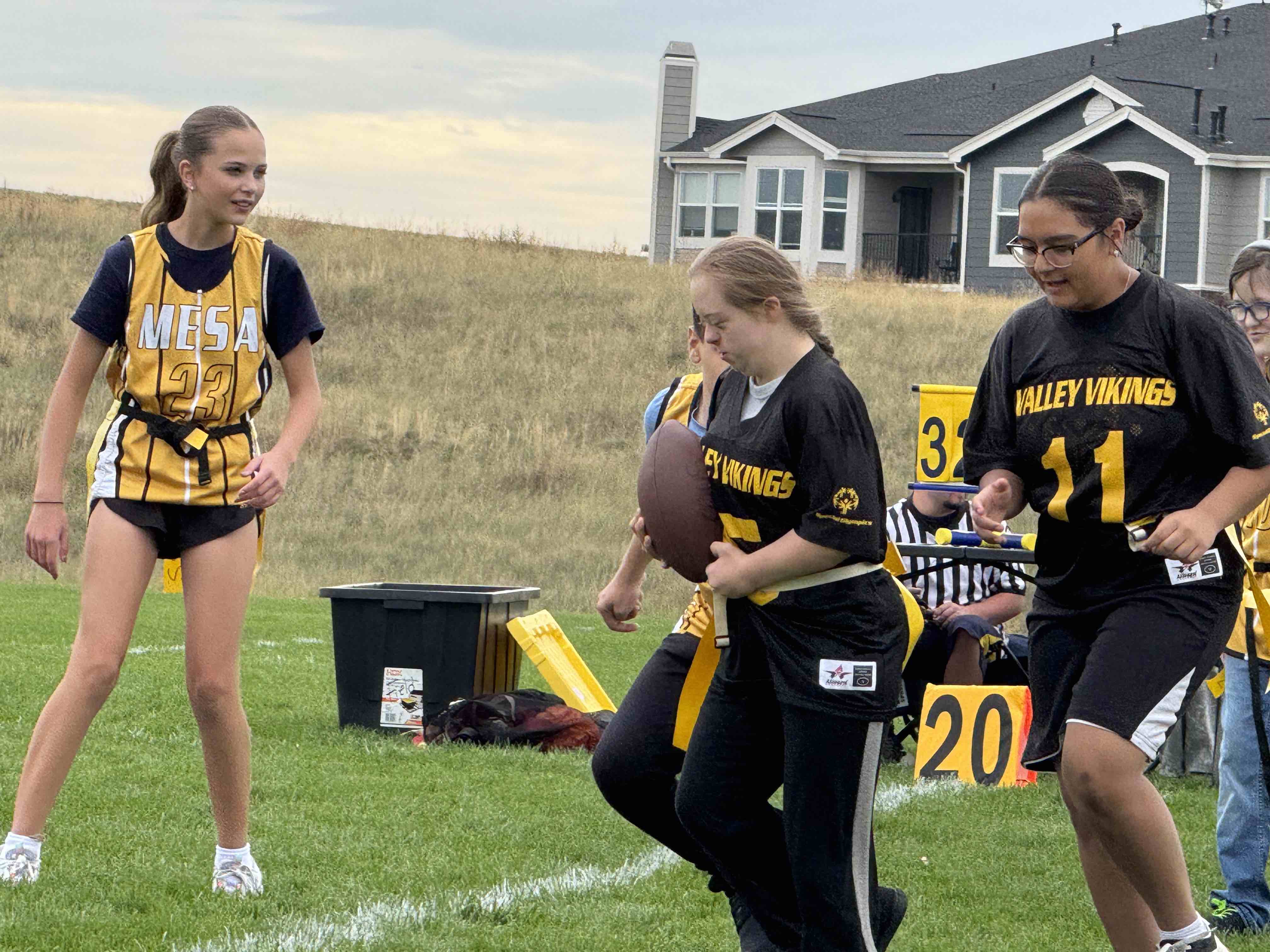 A young child plays flag football and runs down a field.