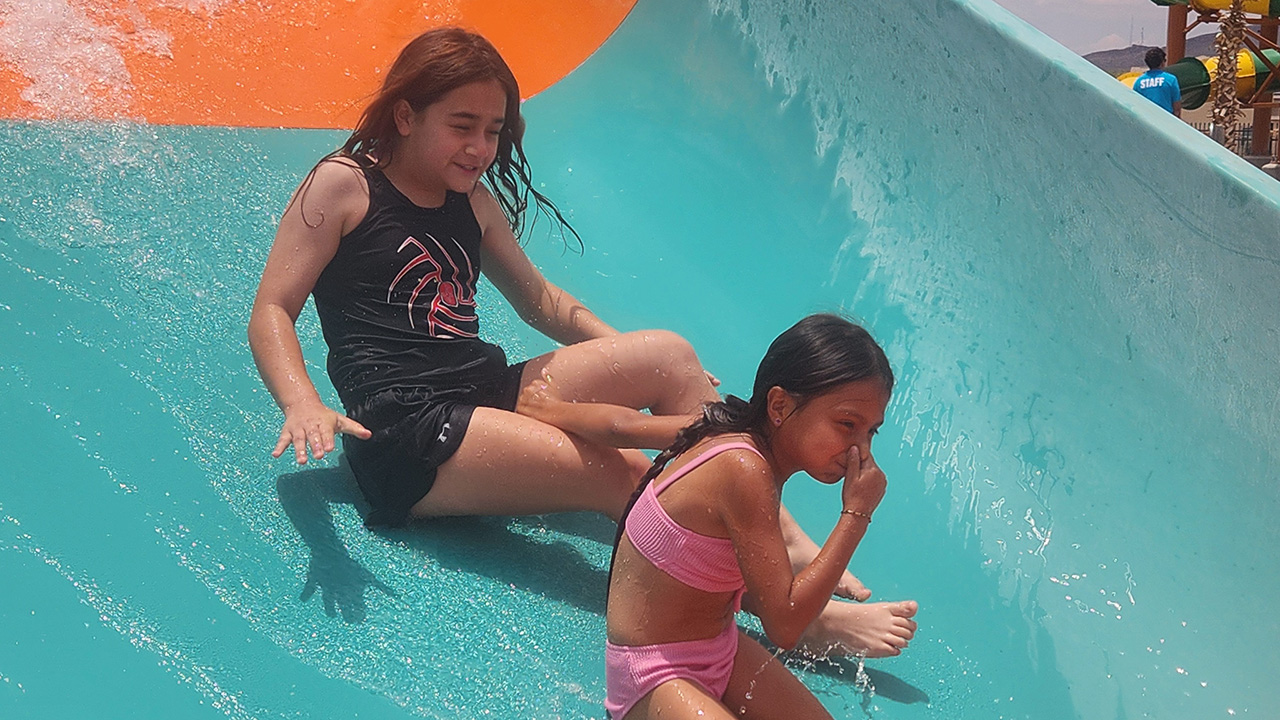 Jaycee and her sister slide on a large water slide at a waterpark.
