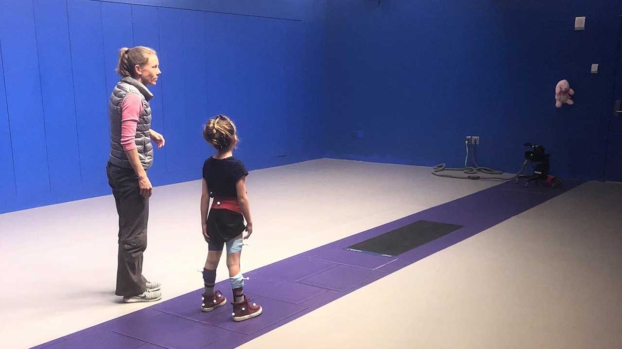 Kendall stands ready to do an exercise with a provider in the gait lab.