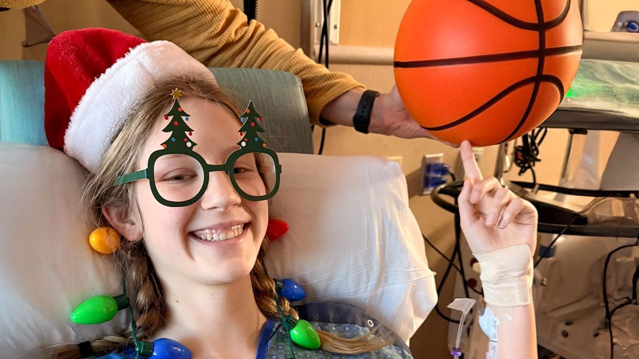 Lydia dressed in Christmas gear pretending to spin a basketball on her pointer finger 