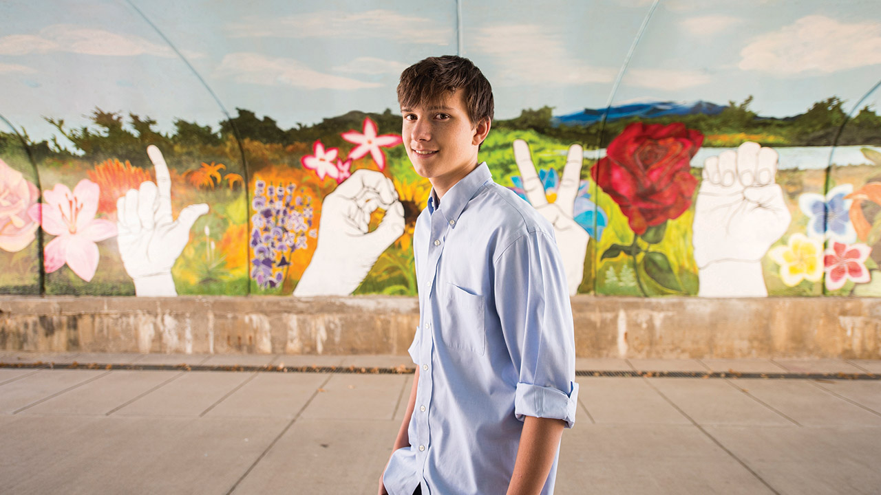 Mathew Fason stands in front of a mural. Mathew is an Eagle Scout, and he based the plan for his mural on the structure of a leadership project he’d done with the Scouts.
