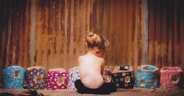 Nora sits in front of her eight casts used for successful congenital scoliosis treatment.