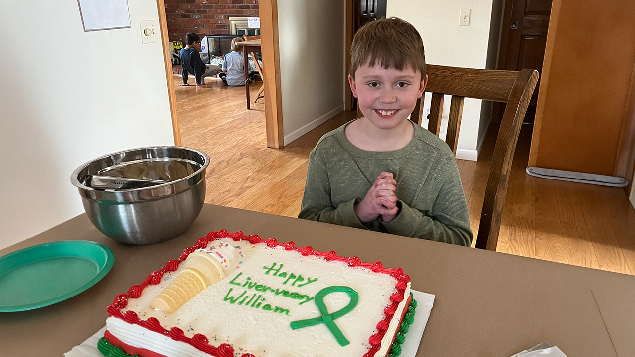 William smiling in front of a birthday cake 