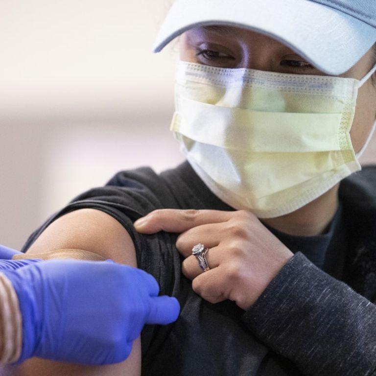 A woman in a mask receives the COVID-19 vaccine.