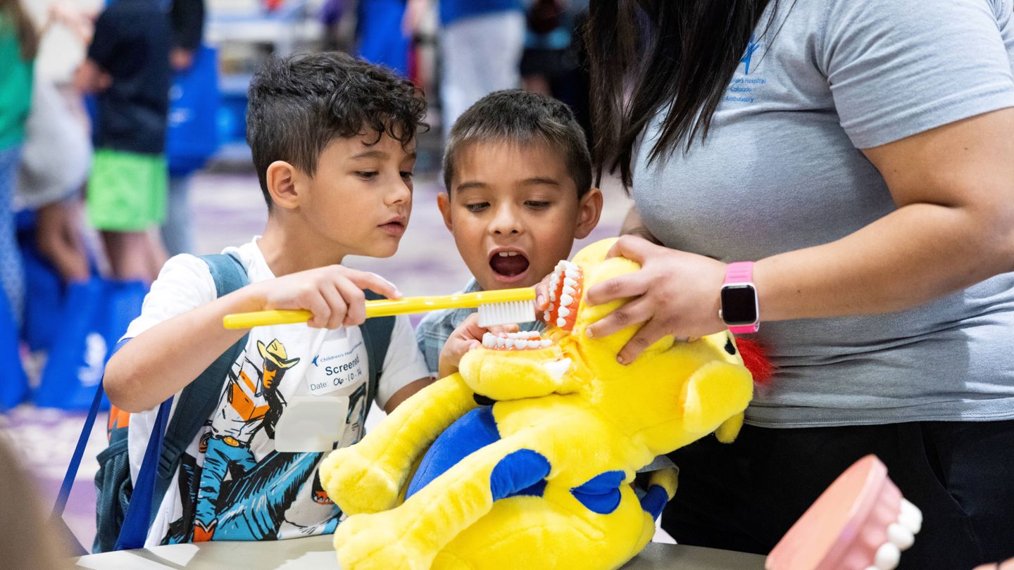 Two children learn how to brush their teeth correctly at Children's Hospital Colorado.