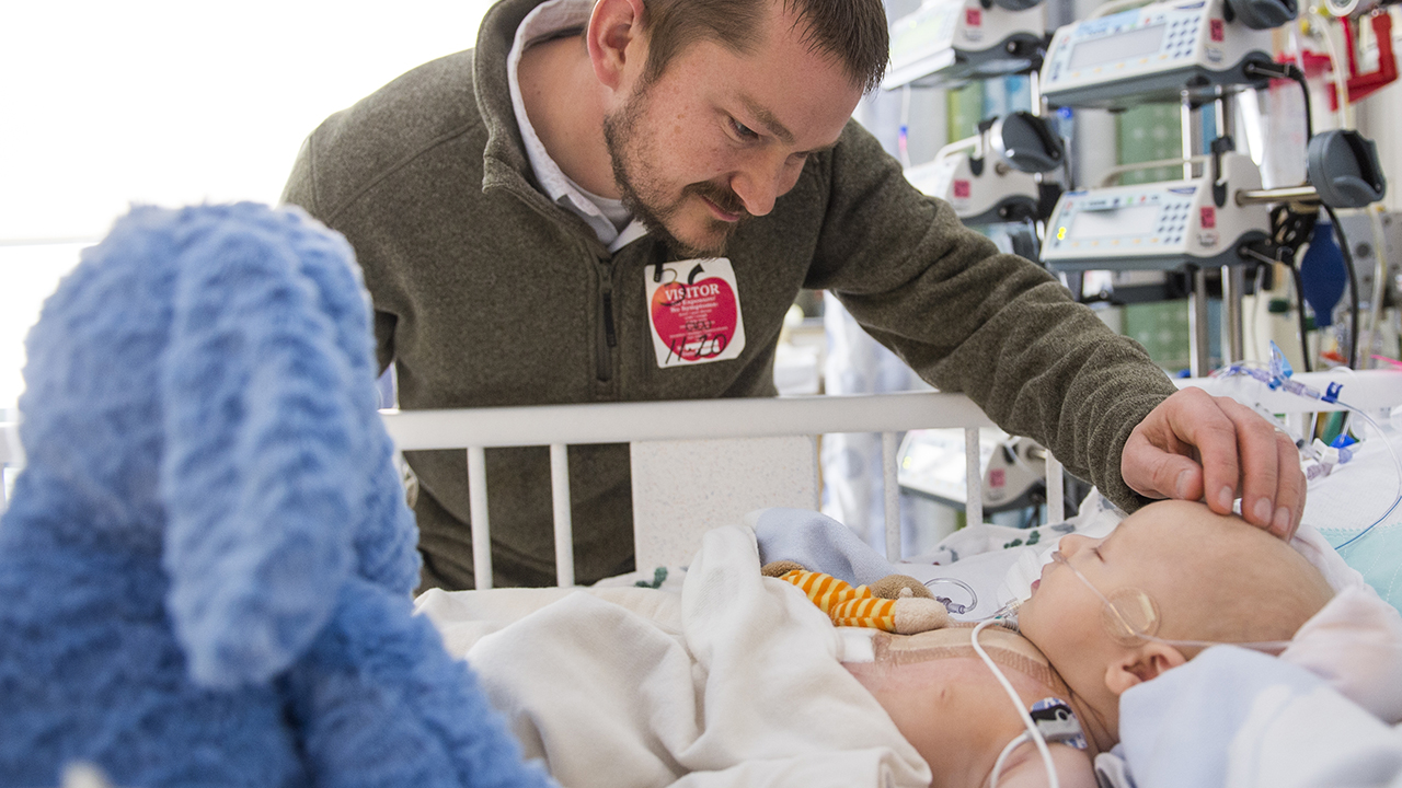 A father check on his child after receiving heart surgery.