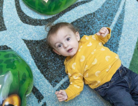 Child laying on the floor on a colorful rug.
