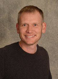 A headshot of heart perfusionist Craig McRobb who has short brown hair and is wearing a brown sweater.