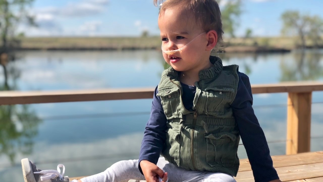 Emma as a young girl sits on a bench by a lake.