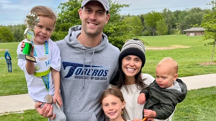 Emma's family of five smiles together while she shows off a trophy and medal. 