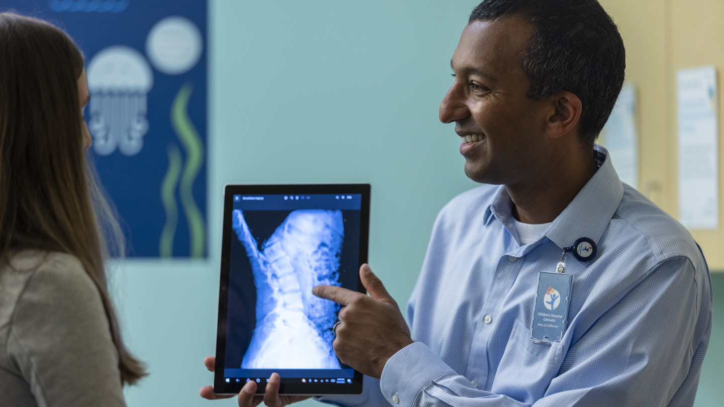 Person showing an x-ray of a spine on a tablet to another person 