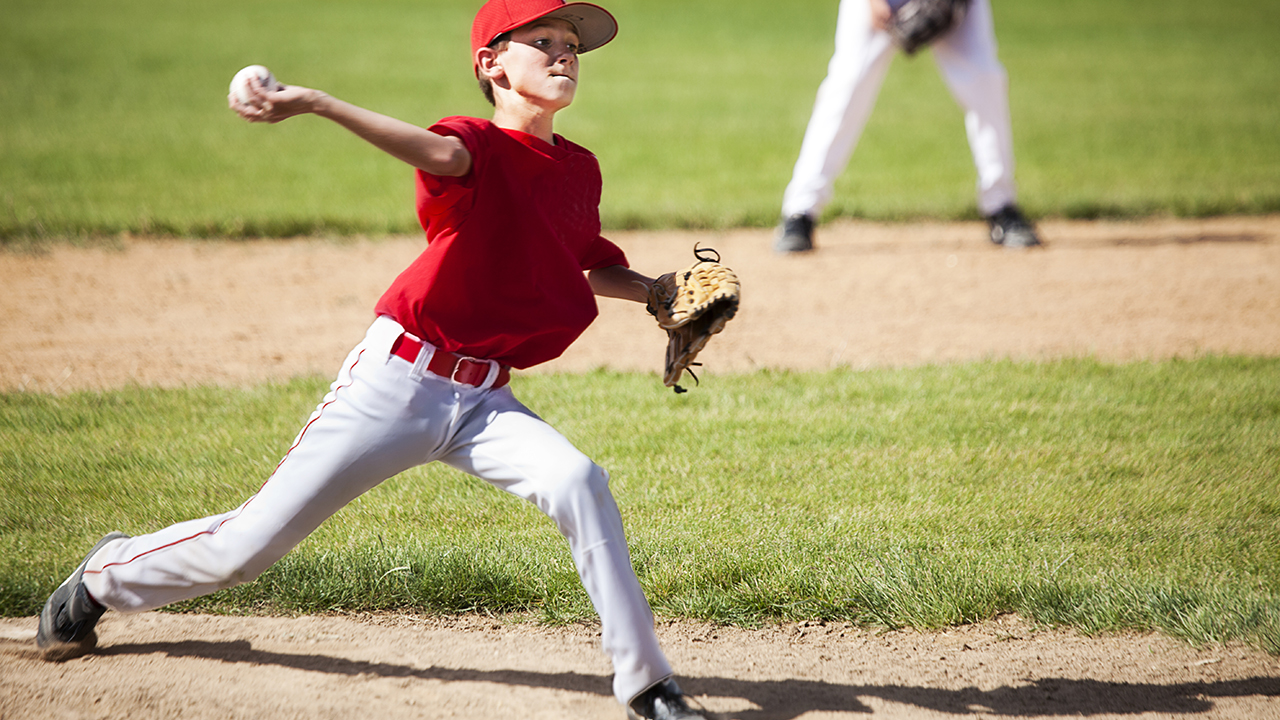 A boy throws a baseball from the pitcher's mound.