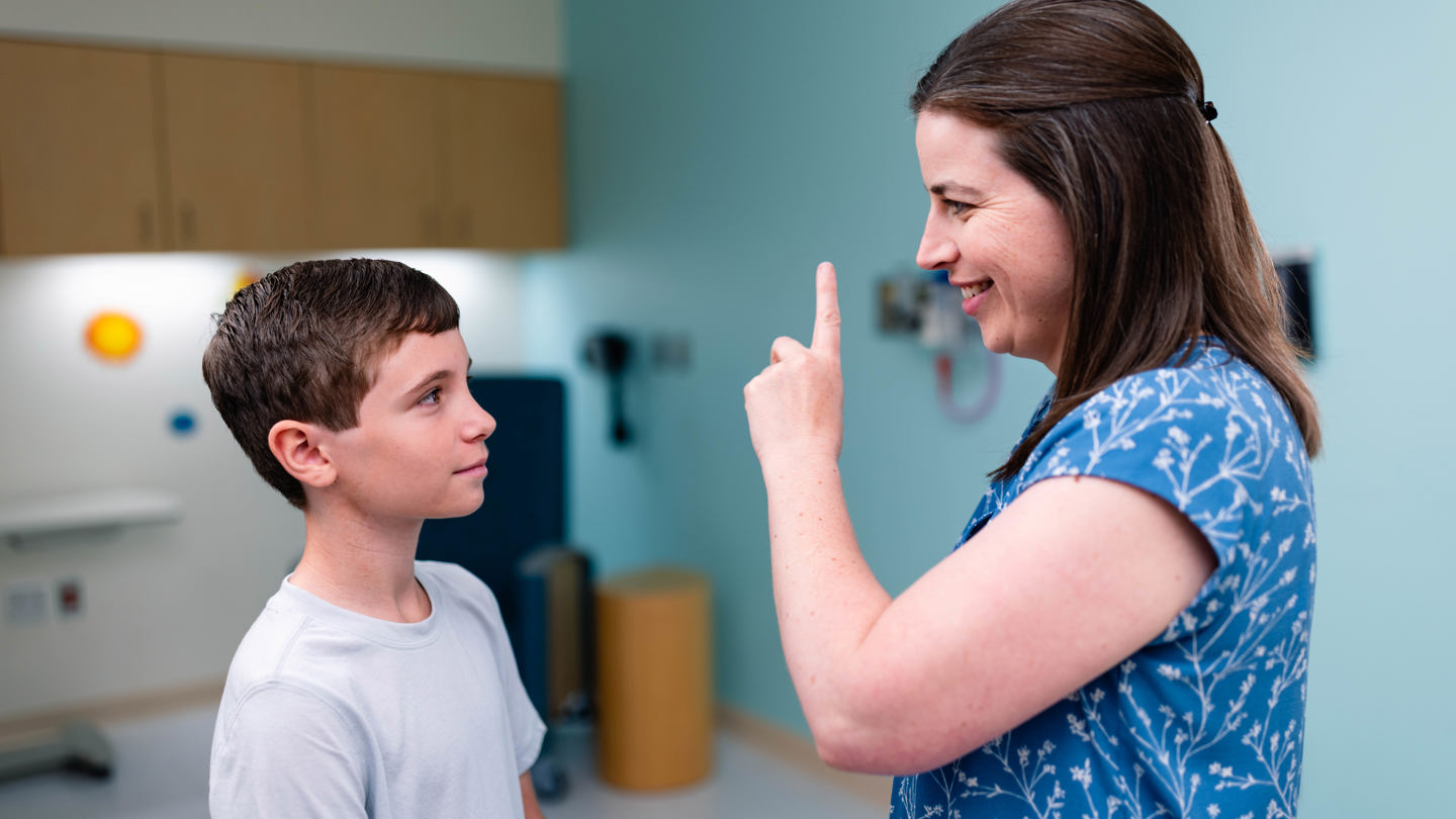 Person holding up pointer finger as child looks at finger 