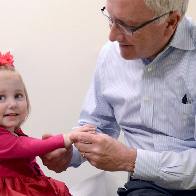 Dr. Frank Scott, Chief of Hand Wrist & Elbow at Children's Hospital Colorado, examines a young girl's hand and wrist.