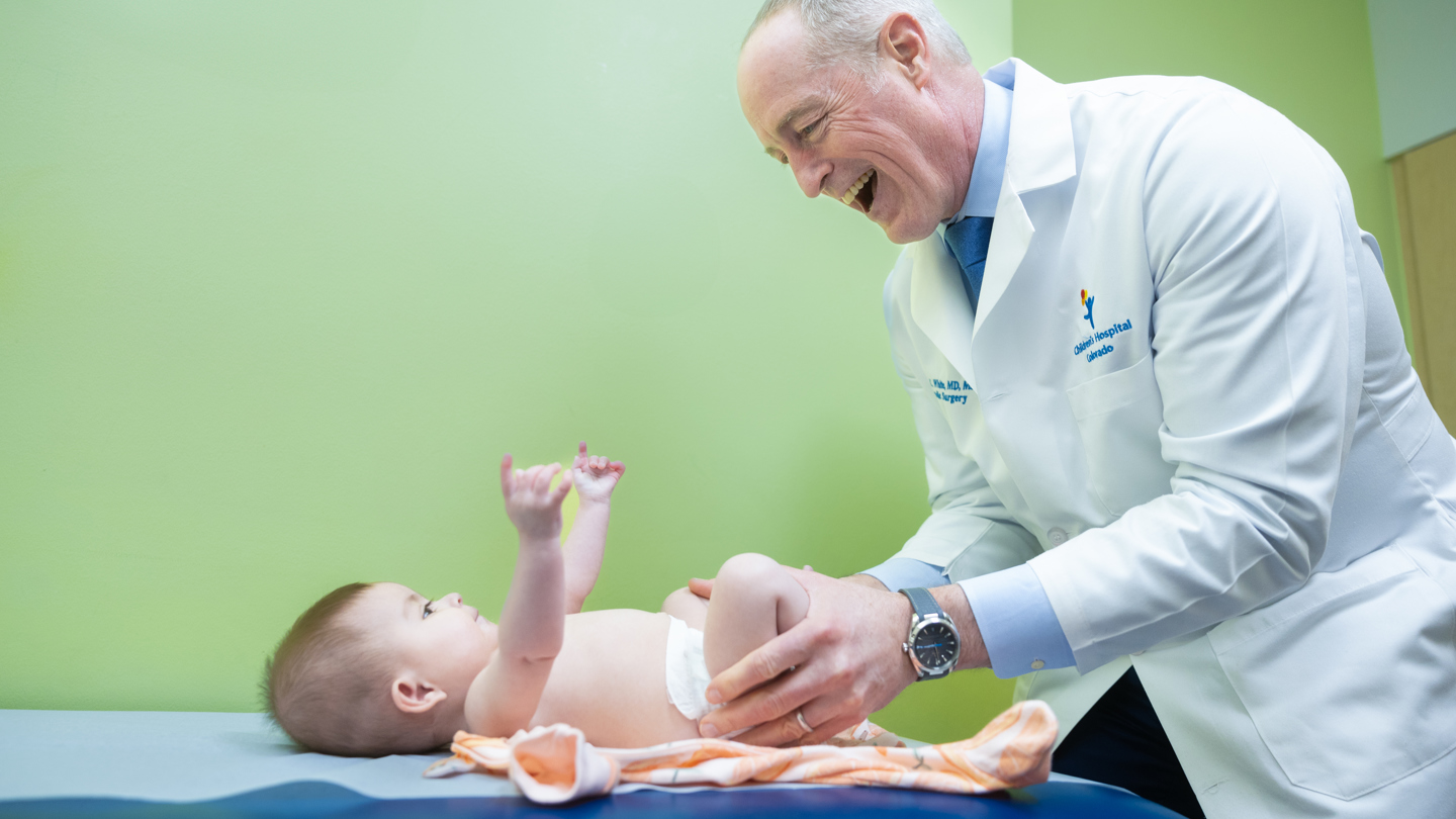 Clinician smiling at baby who is laying on clinician table 