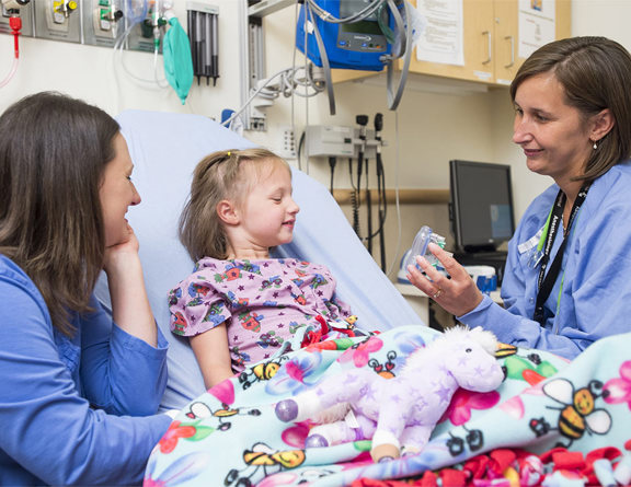 A doctor explains to a child patient what will happen during her operation at Children's Hospital Colorado.