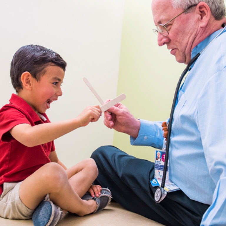 Doctor playing with a patient, pretending the tongue depressors are swords.
