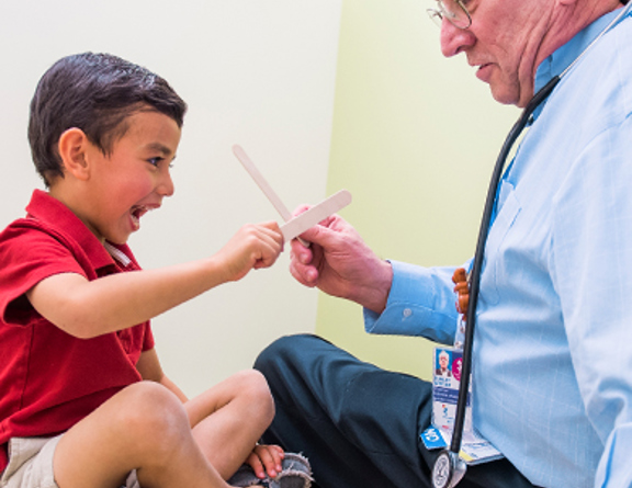 Doctor playing with a patient, pretending the tongue depressors are swords.