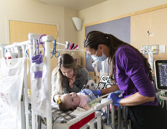 Nurses practicing specialized neonatal care techniques on a medical mannequin.