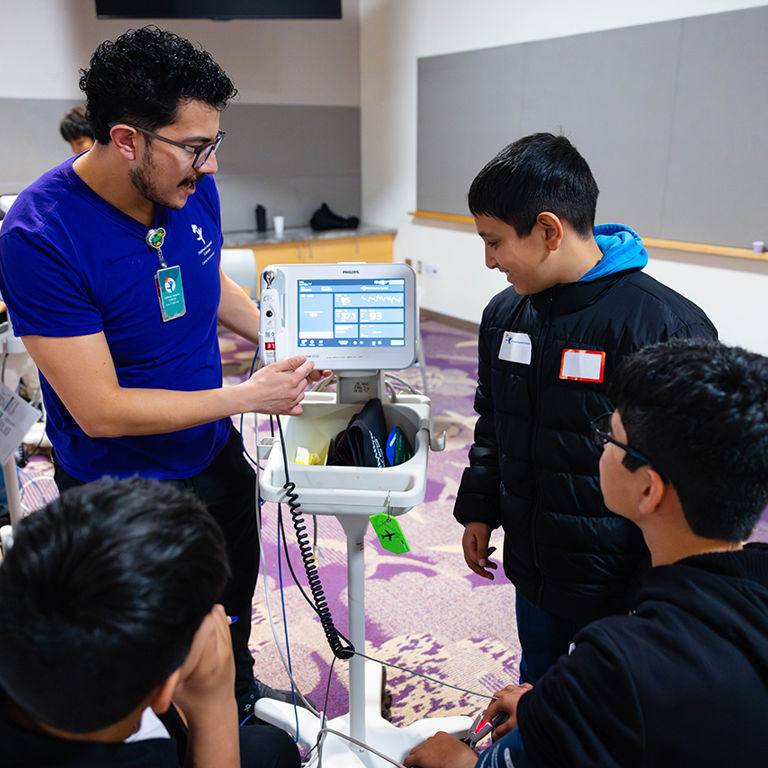 Middle school students and male nursing leaders participating in medical workshops.