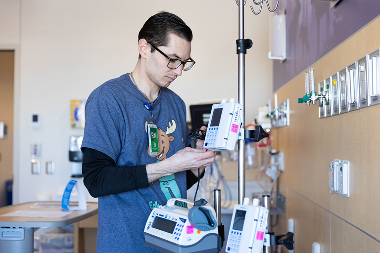A healthcare team member in blue scrubs preparing medication in a specialized hospital unit.