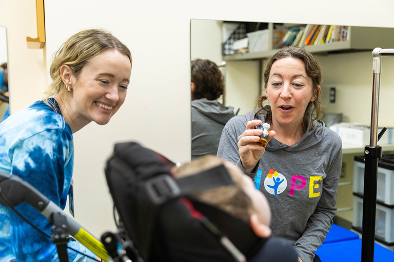 A clinician interacting warmly with a young patient in a colorful hospital playroom.