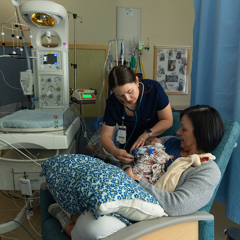 Alex Symes coaching a nurse at the bedside in the Cardiac Intensive Care Unit.