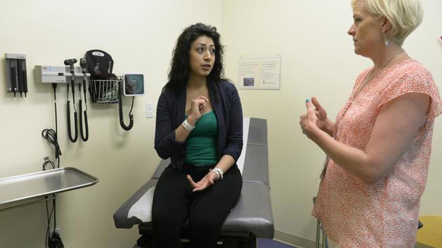 Dr. Liz Romer, director of Children's Colorado Family Planning Clinic, talks to a teenage girl in an exam room.